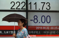 A woman walks past an electronic stock board showing Japan's Nikkei 225 index at a securities firm Wednesday, Aug. 22, 2018, in Tokyo. Asian shares were mixed Wednesday, as some markets were cheered by bullish sentiments on Wall Street despite concerns about an ongoing trade dispute with China. (AP Photo/Eugene Hoshiko)