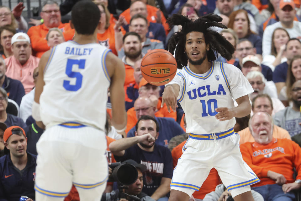 UCLA guard Tyger Campbell (10) passes to guard Amari Bailey (5) during the first half of the team's NCAA college basketball game against Illinois on Friday, Nov. 18, 2022, in Las Vegas. (AP Photo/Chase Stevens)