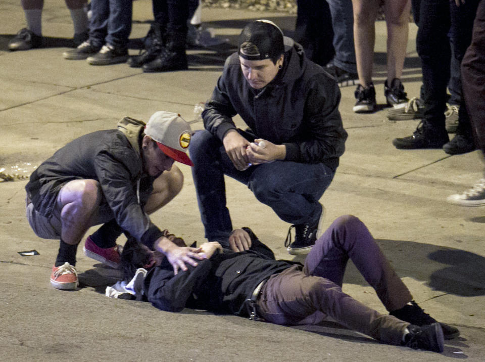 Bystanders tend to a man who was struck by a vehicle on Red River Street in downtown Austin, Texas, on Wednesday March 12, 2014. Police say two people were confirmed dead at the scene after a car drove through temporary barricades set up for the South By Southwest festival and struck a crowd of pedestrians. (AP Photo/Austin American-Statesman, Jay Janner)