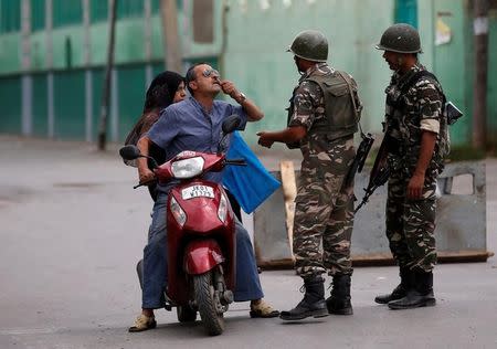 A man shows his tooth to Indian policemen as he seeks permission to see a doctor after he was stopped during a curfew in Srinagar July 19, 2016. REUTERS/Danish Ismail