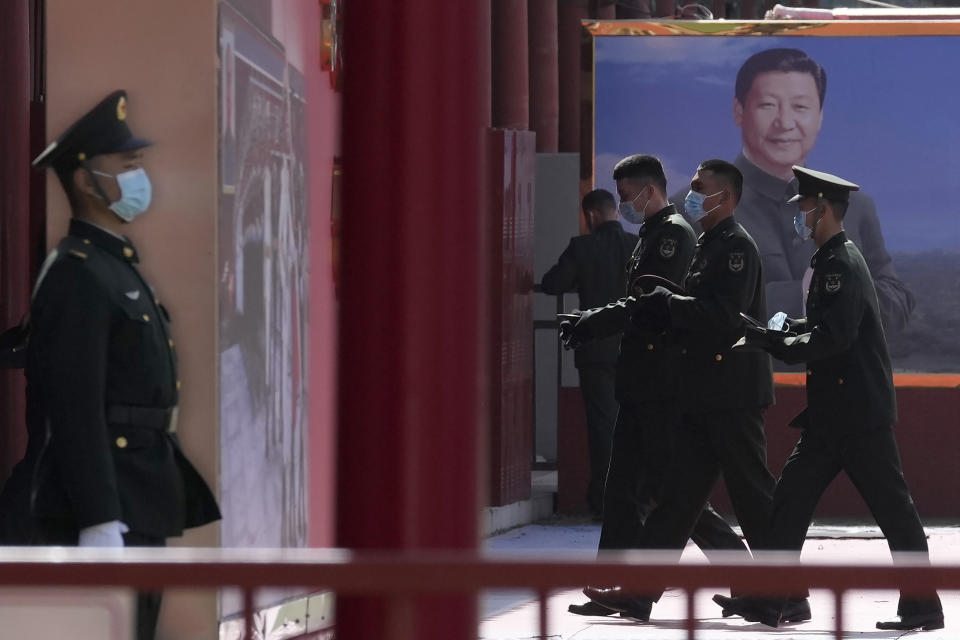 Chinese military personnel pass by a board displaying a photo of Chinese President Xi Jinping on March 4, 2022, in Beijing. A conflict with China, which threatens to invade Taiwan, would be a disaster for all sides regardless of the outcome, Taiwan's defense minister said Thursday, March 10, 2022. (AP Photo/Ng Han Guan)