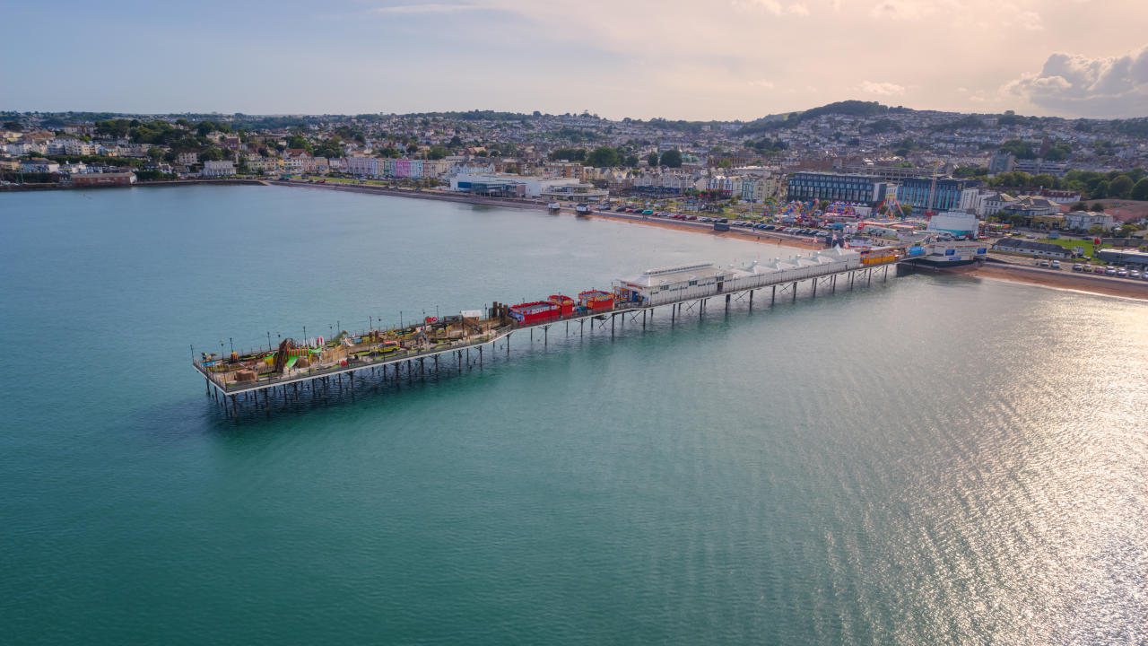 Sunlight falls onto the sea surrounding the Victorian Pier at Paignton, Devon, England