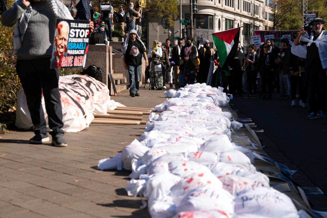 Protesters place white sacks representing the bodies of people killed in Gaza during a pro-Palestinian demonstration at Freedom Plaza in Washington, Saturday, Nov. 4, 2023 (AP)
