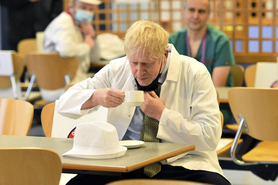 Britain's Prime Minister Boris Johnson drinks tea in the canteen during a visit to Royal Berkshire Hospital, Reading, England, Monday Oct. 26, 2020, to mark the publication of a new review into hospital food. (Jeremy Selwyn/Pool via AP)