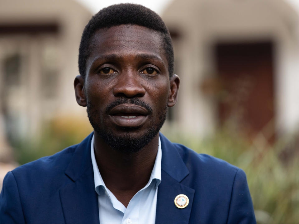 <p>Wine speaks to reporters as security forces surround his home on 15 January (the day after the election) in Kampala, Uganda</p> (Getty)