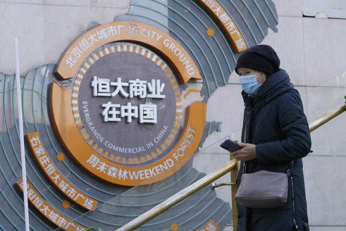 A woman passes by a display showing Evergrande's China commercial projects in Beijing, China, Tuesday, Dec. 7, 2021. Financial markets can cope with the Chinese real estate developer that is struggling to avoid defaulting on $310 billion in debt, the central bank governor said Thursday, Dec. 9, 2021, in a new effort to assure the public the economy can be shielded from fallout. (AP Photo/Ng Han Guan)