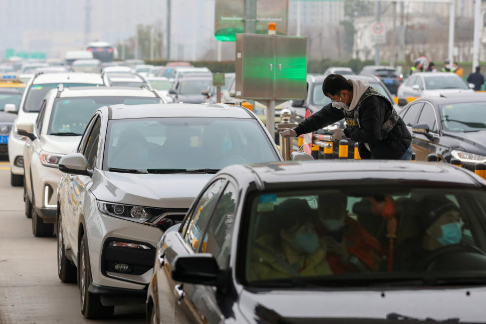 Un miembro del personal de un equipo local de prevención de epidemias verifica la temperatura corporal de la gente que circula en coche. (Foto: China Daily / Reuters).