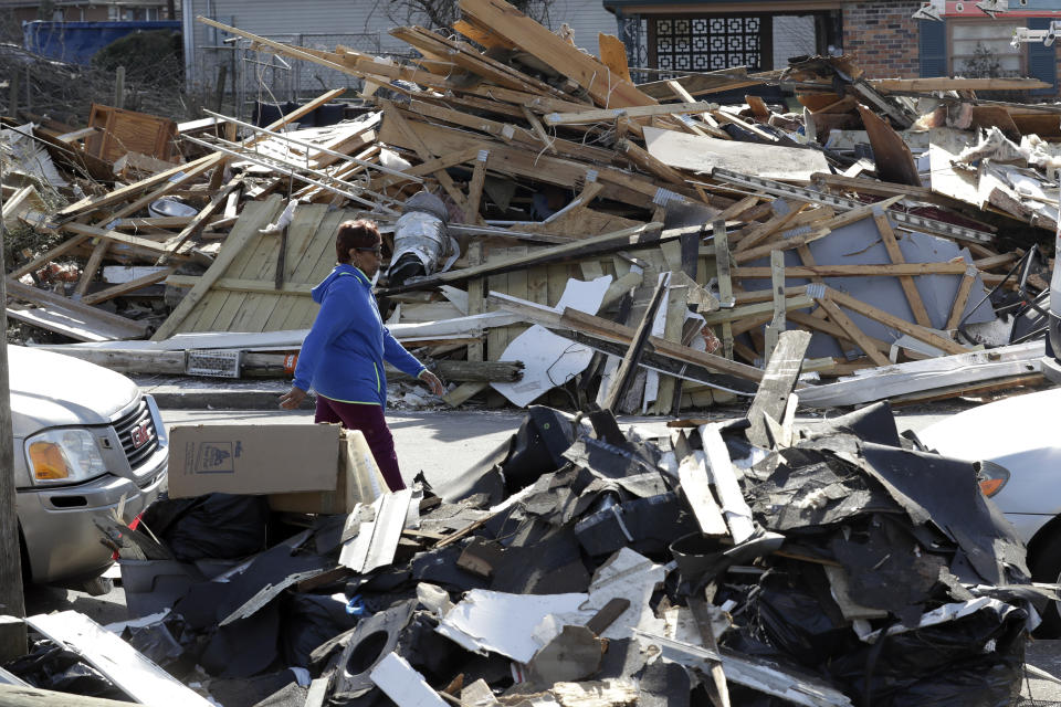 A woman walks down a street lined with debris Friday, March 6, 2020, in Nashville, Tenn. Residents and businesses face a huge cleanup effort after tornadoes hit the state Tuesday. (AP Photo/Mark Humphrey)