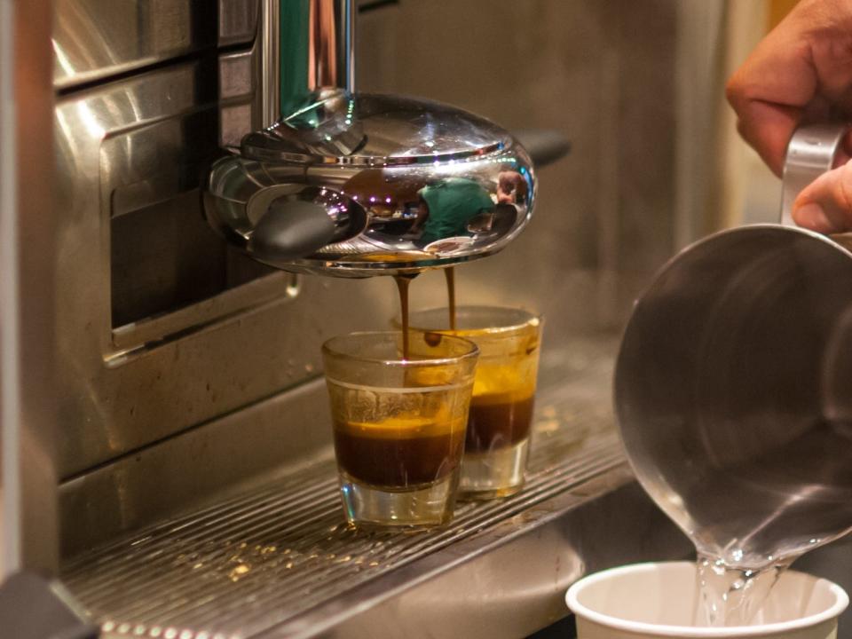 starbucks barista making a drink in front of espresso machine with two shots of espress on it