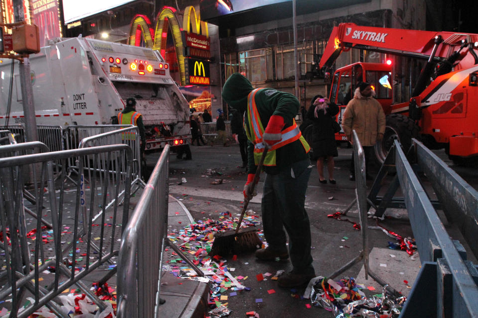 A sanitation worker sweeps up debris in New York's Times Square early New Year's Day Wednesday Jan. 1, 2014. (AP Photo/Tina Fineberg)