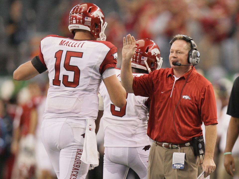 In this Oct. 9, 2010, file photo, Arkansas head coach Bobby Petrino, right, congratulates quarterback Ryan Mallett (15) after a first half touchdown against Texas A&M during an NCAA college football game at Cowboys Stadium in Arlington, Texas. A person familiar with the situation says Petrino is out as the football coach at Arkansas. The person spoke to The Associated Press on the condition of anonymity, and the university has scheduled a Tuesday evening news conference with athletic director Jeff Long. (AP Photo/Mike Fuentes, File)