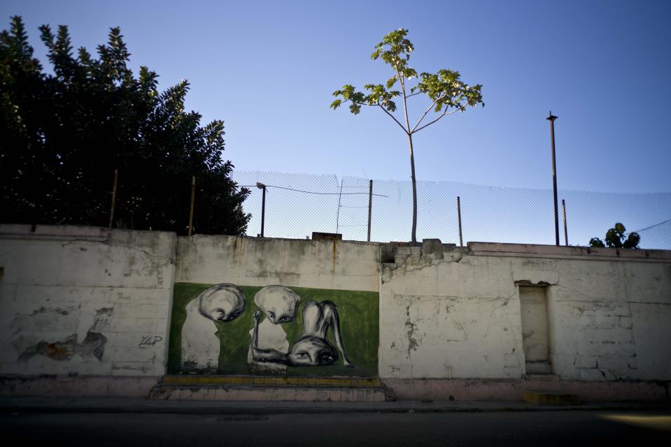 In this Feb. 12, 2017 photo, work of urban artist Yulier P. adorns a wall on a street in Old Havana, Cuba. The 27-year-old artist, whose full name is Yulier Rodríguez Pérez says, "The urban artist questions society and politics, the realities of life in the streets," which for him includes a sense of helplessness and frustration over the struggles of daily life that may not fit with the image many have of Cuba. (AP Photo/Ramon Espinosa)