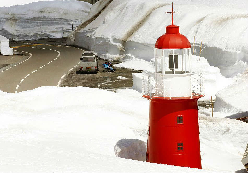 Dutch tourists relax in front of a lighthouse on the Central Swiss Oberalp Pass mountain pass, located at 2,046 metres (6,713 ft) above sea level.