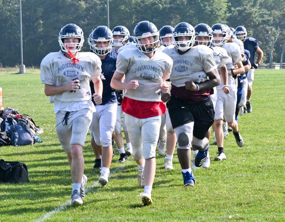 The Monomoy high football team circles the field at the start of practice lead by Jake Vagenas (right) and Jack McCarty.