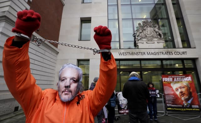 A demonstrator supporting Julian Assange wears a mask and chains outside court 