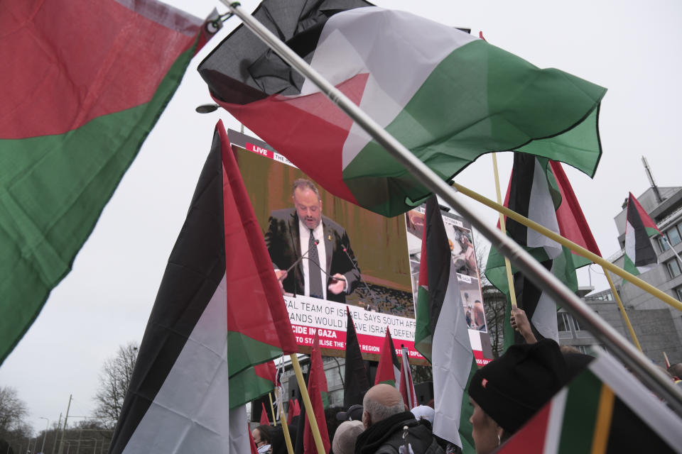 Protesters carry flags and banners outside the International Court of Justice in The Hague, Netherlands, Friday, Jan. 12, 2024. The United Nations' top court opened hearings Thursday into South Africa's allegation that Israel's war with Hamas amounts to genocide against Palestinians, a claim that Israel strongly denies. (AP Photo/Patrick Post)