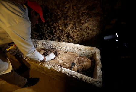 A Egyptian archaeologist examines a mummy in a coffin inside a tomb during the presentation of a new discovery at Tuna el-Gebel archaeological site in Minya Governorate, Egypt, February 2, 2019. REUTERS/Amr Abdallah Dalsh