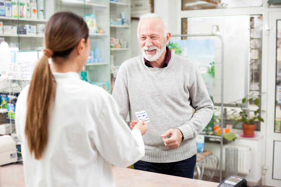 Happy senior male customer buying medications at drugstore