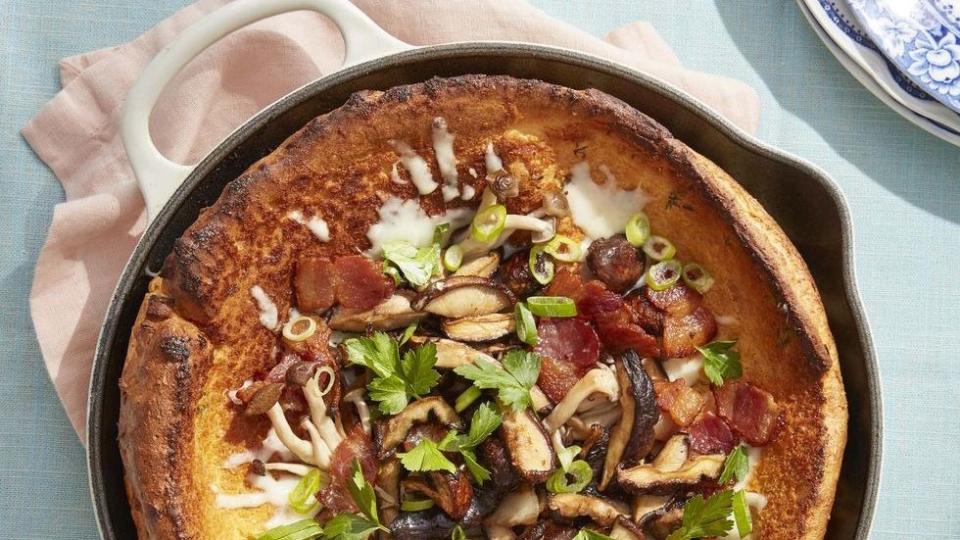 roasted mushroom and bacon dutch baby in a white enamel cast iron skillet