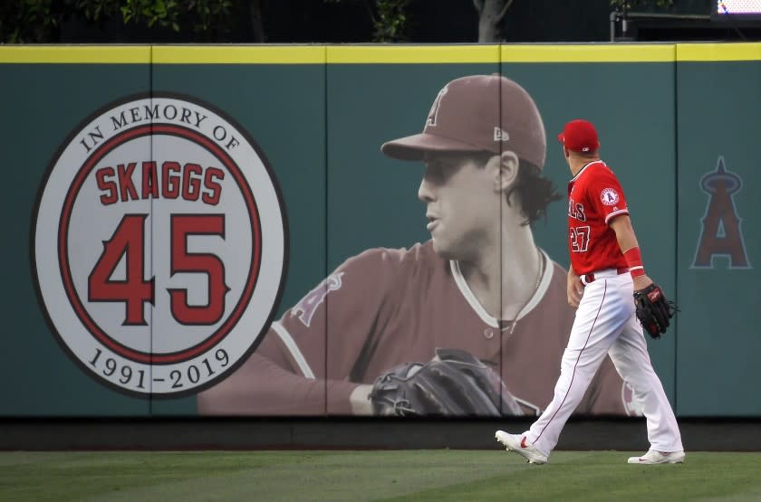 Los Angeles Angels center fielder Mike Trout walks by a picture of Tyler Skaggs in center field prior to a baseball game against the Baltimore Orioles, Thursday, July 25, 2019, in Anaheim, Calif. Skaggs died on July 1. (AP Photo/Mark J. Terrill)