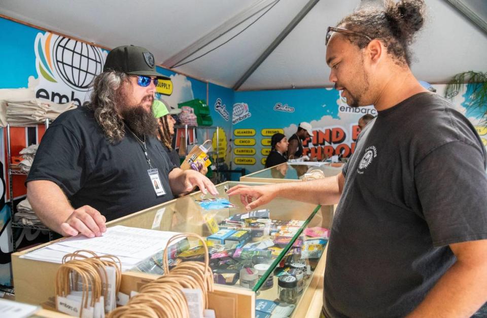 Independent budtender Tyler Sherlock, left, explains purchase options for cannabis products to a customer in the vendor area of the cannabis exhibit at the California State Fair in Sacramento on Tuesday. “I want to be part of it just for the historic aspect,” Sherlock said regarding his participation in California’s first state-sanctioned fair permitting on-site cannabis product sales and consumption.