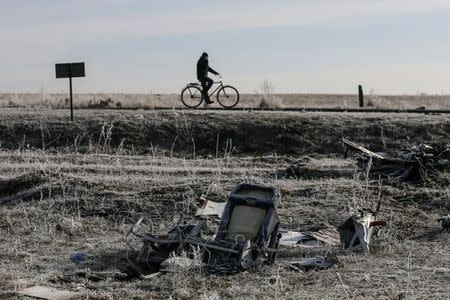 A man rides his bicycle past the wreckage of MH17, a Malaysia Airlines Boeing 777 plane, at the site of the plane crash near the village of Hrabove (Grabovo) in Donetsk region, December 15, 2014. REUTERS/Maxim Shemetov