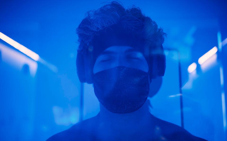 A young adult male in a cryotherapy chamber in a biohacking lab