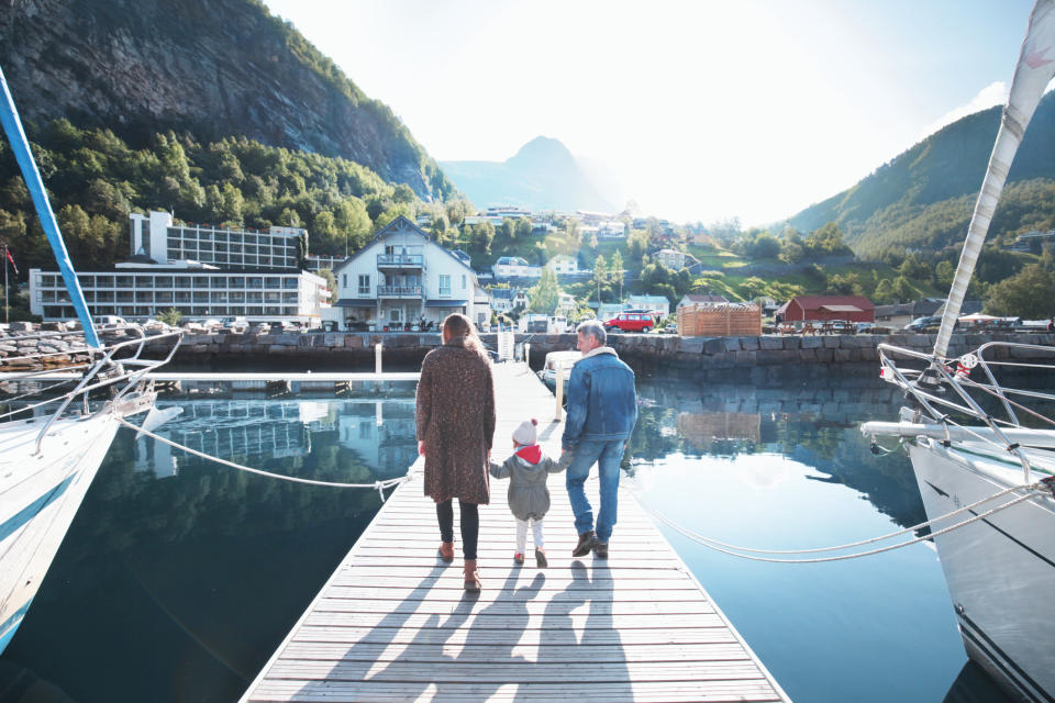 Family walking on pier at sunny day.