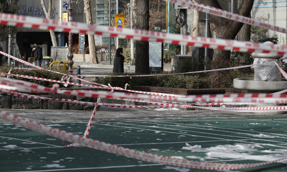 People wearing face masks walk near a park, which is taped for the social distancing measures and a precaution against the coronavirus in Seoul, South Korea, Thursday, Jan. 14, 2021. (AP Photo/Lee Jin-man)