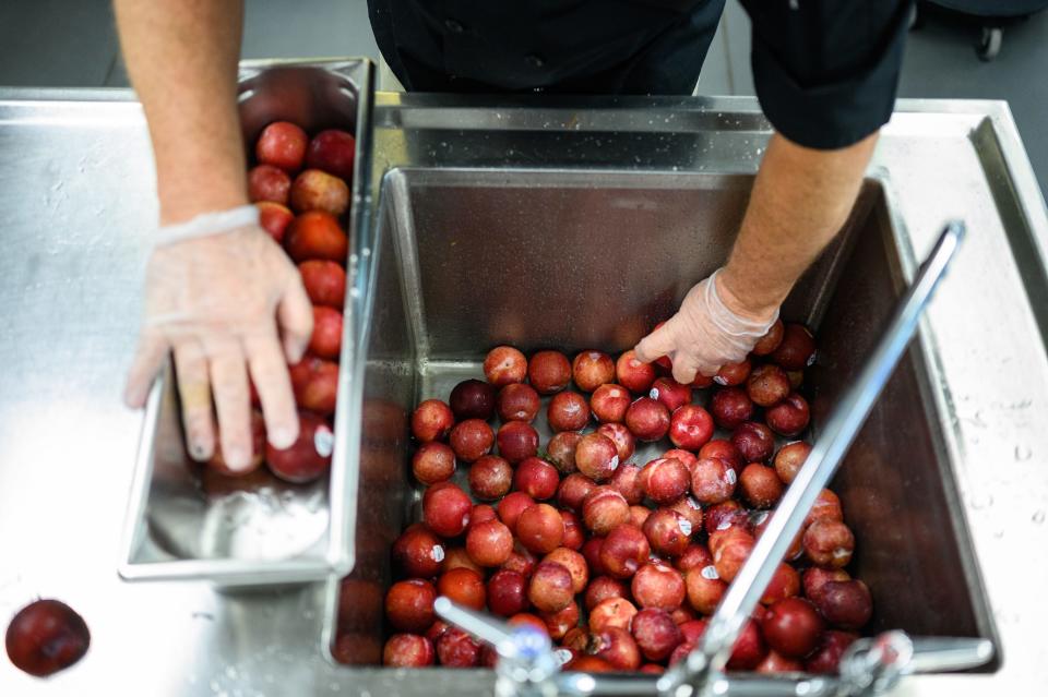 Chris Morgan washes fruit in the Dr. Phinnize J. Fisher Middle School cafeteria kitchen Friday, Aug. 20, 2021.