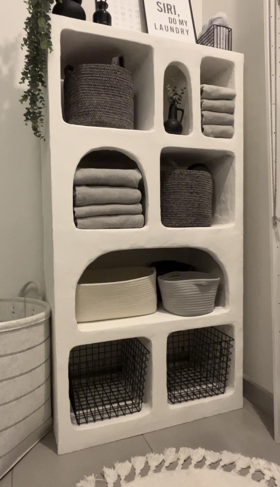 A customized shelf with rustic textured storage shelves housing folded laundry