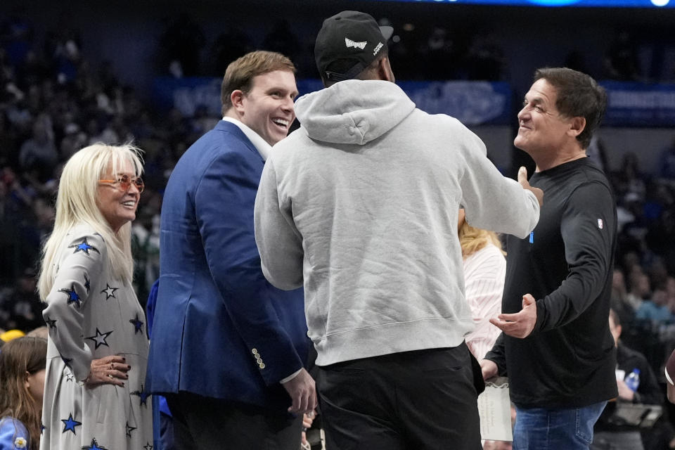 From left to right, Miriam Adelson, controlling shareholder of the Las Vegas Sandals Corp., Dallas Mavericks Governor Patrick Dumont, Dallas Cowboys' Micah Parsons and Mavericks alternate Governor Mark Cuban, right, talk on the sideline as they attend an NBA basketball game between the Phoenix Suns play the Mavericks in the first half in Dallas, Thursday, Feb. 22, 2024. (AP Photo/Tony Gutierrez)