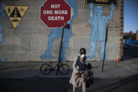 A woman wearing a mask crosses the street in front of a mural about traffic accidents reading, "NOT ONE MORE DEATH" in the Brooklyn borough of New York, March 27, 2020. (AP Photo/Wong Maye-E)