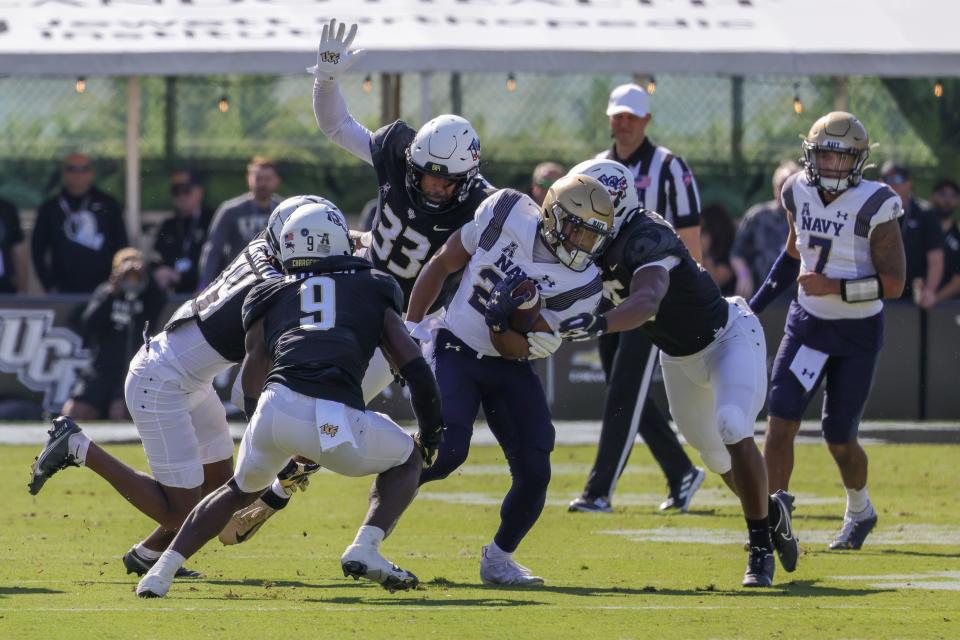 Nov 19, 2022; Orlando, Florida, USA; Navy Midshipmen wide receiver Maquel Haywood (24) is tackled by UCF Knights linebacker Jason Johnson (15) during the first quarter at FBC Mortgage Stadium. Mandatory Credit: Mike Watters-USA TODAY Sports