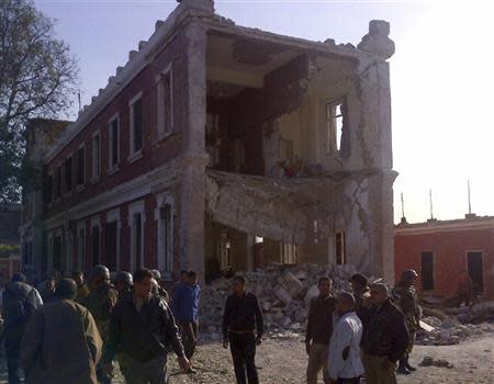 People and army personnel stand around a damaged bulding after an explosion in Egypt's Nile Delta town of Anshas, about 100 km (65 miles) northeast of Cairo, December 29, 2013. REUTERS/Stringer