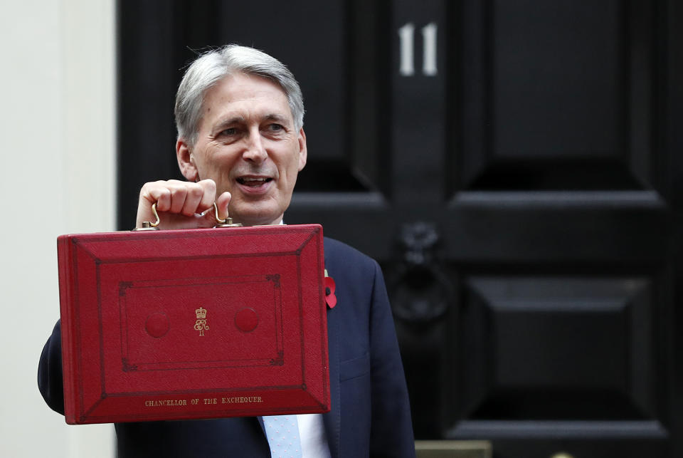 Philip Hammond holds up the traditional red dispatch box outside his official residence 11 Downing Street before delivering his annual budget speech .(AP Photo/Frank Augstein)