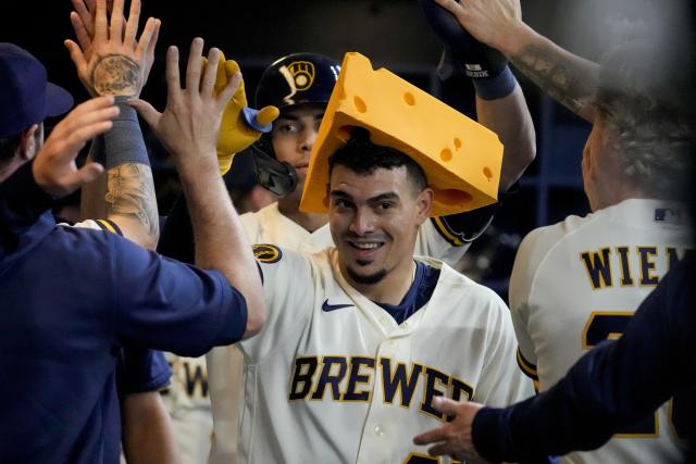 Milwaukee Brewers' Willy Adames, left, places a cheesehead on Tyrone Taylor  (15) as Taylor returns to the dugout after hitting a solo home run off  Colorado Rockies starting pitcher Connor Seabold in