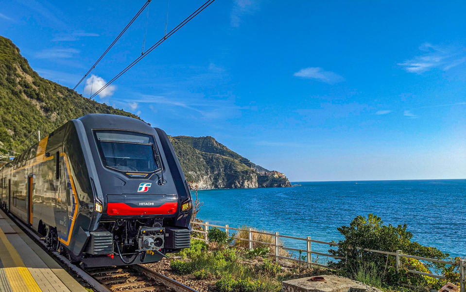 A sleek, black train gliding along the Mediterranean coast.