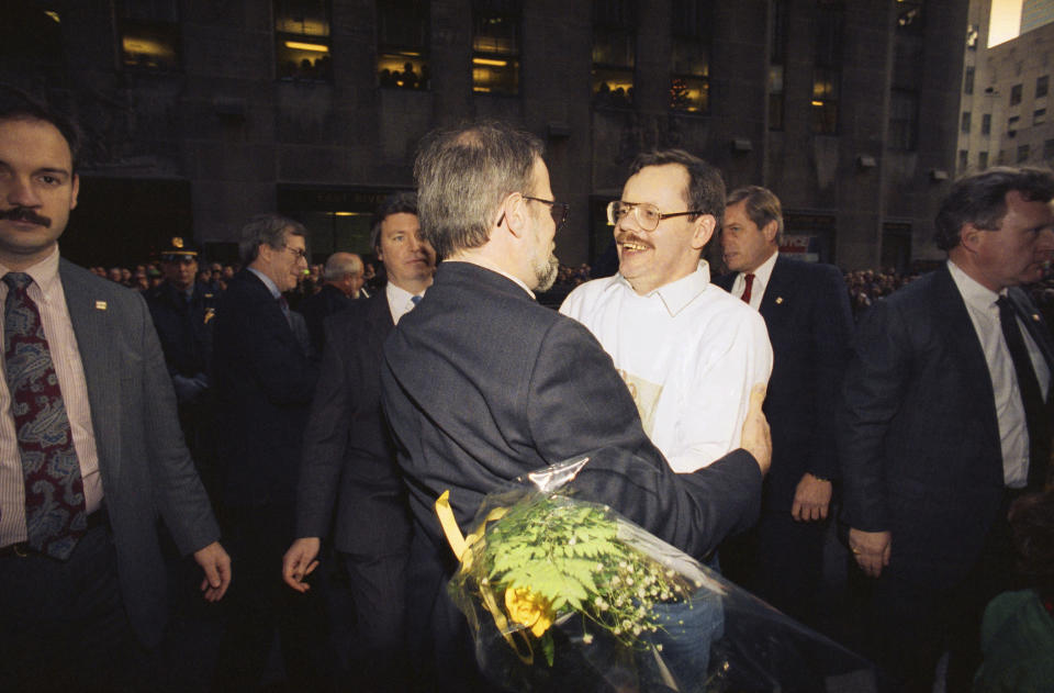 FILE - Former hostage and Associated Press chief Middle East correspondent Terry Anderson, center right, hugs Associated Press Deputy International Editor Nick Tatro, his predecessor in Beirut, outside the Associated Press headquarters in New York, Dec. 10, 1991. Anderson, the globe-trotting AP correspondent who became one of America’s longest-held hostages after he was snatched from a street in war-torn Lebanon in 1985 and held for nearly seven years, died Sunday, April 21, 2024, at age 76. (AP Photo/Mark Lennihan, File)