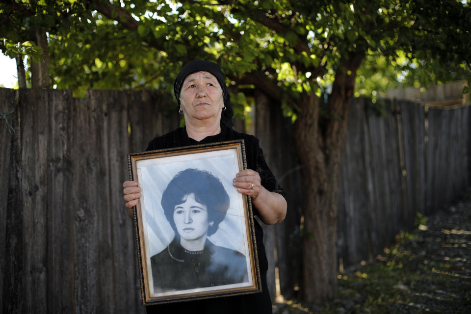 In this picture taken Wednesday, May 22, 2019, Marioara Banea, a 63-year-old local retiree poses with a 1974 portrait of herself, in Luncavita, Romania. The Romania village of Luncavita has benefited greatly from millions in development funds from the European Union, but few of its residents bothered to vote in previous European Parliamentary elections. “The EU changed my life,” Banea said. “Now we have water. We used to queue at the well for hours ... and we have indoor plumbing too!” (AP Photo/Vadim Ghirda)