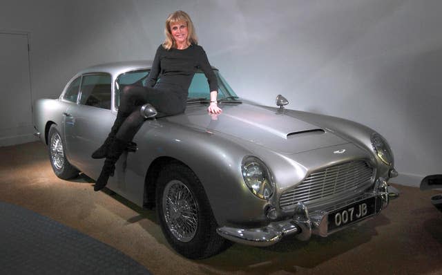 Ekland on the bonnet of an original Aston Martin DB5, an iconic Bond car