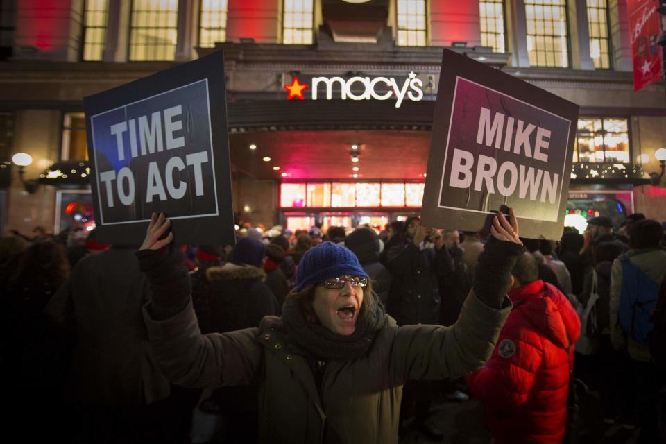 A protester holds signs aloft outside Macy's before the kick off of Black Friday sales in New York