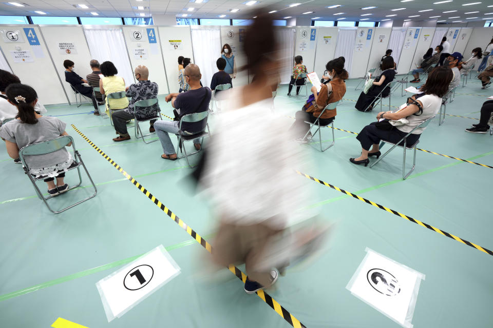 FILE - In this June 30, 2021, file photo, local residents over 40 years old wait for the Moderna COVID-19 vaccine at a vaccination center in the Sumida ward of Tokyo. Japan has resisted lockdowns even as cases have risen to record levels. It has instead relied on widespread mask use and emphasized its vaccination campaign, which began slowly but has accelerated to more than 1 million shots a day. (AP Photo/Eugene Hoshiko, File)