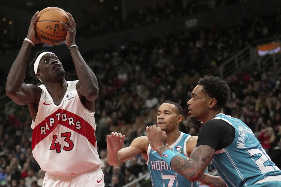 Toronto Raptors forward Pascal Siakam (43) eyes the basket under pressure from Charlotte Hornets guard Bryce McGowens (7) and teammate P.J. Washington (25) during the second half of an NBA basketball game in Toronto, Monday, Dec. 18, 2023. (Nathan Denette/The Canadian Press via AP)