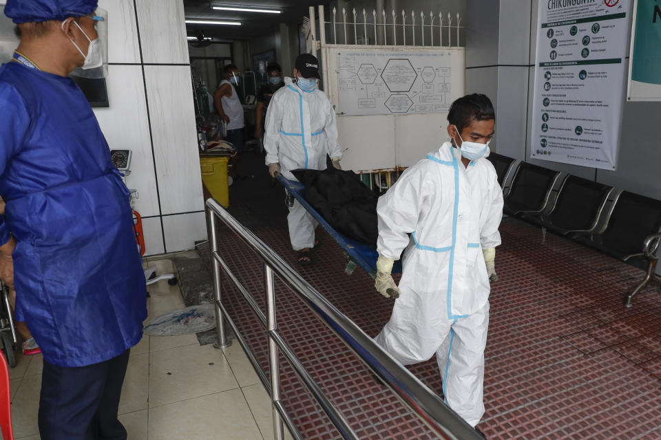 Funeral workers wearing protective suits carry a person who died due to COVID-19 complications at a hospital in Manila, Philippines on Monday, April 26, 2021. COVID-19 infections in the Philippines surged past 1 million Monday in the latest grim milestone as officials assessed whether to extend a monthlong lockdown in Manila and outlying provinces amid a deadly spike or relax it to fight recession, joblessness and hunger. (AP Photo/Aaron Favila)