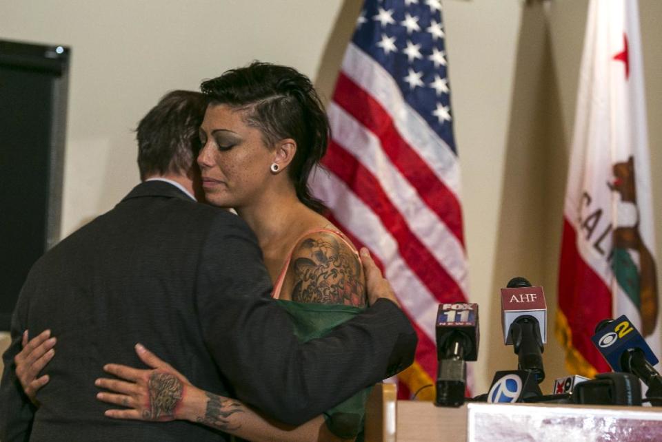 Michael Weinstein, AIDS Healthcare Foundation president, left, hugs Cameron Bay, an adult film performer who became infected with HIV while working in the industry in August 2013, during a news conference sponsored by AHF at its Public Health Division building in Los Angeles on Wednesday, Sept. 18, 2013. Bay spoke out about her treatment by the porn industry. Industry officials say the recent infections have not been tracked back to film sets and most likely occurred through the actors' private lives. (AP Photo/Damian Dovarganes)