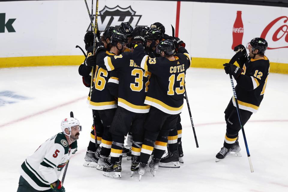 The Boston Bruins celebrate a goal by Taylor Hall in overtime as Minnesota Wild's Jacob Middleton (5) skates off the ice following an NHL hockey game, Saturday, Oct. 22, 2022, in Boston. (AP Photo/Michael Dwyer)