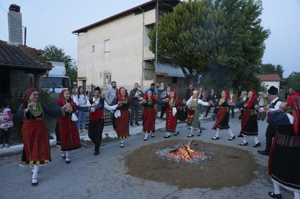 Dancers dressed in traditional Thrace costumes dance around a fire set up in a residential street for a firewalking ritual in Lagkadas, Greece, on Monday, May 22, 2023. Groups of devotees of St. Constantine called "anastenaria" celebrate his feast day with elaborate rituals that include carrying icons over a bed of burning coals. (AP Photo/Giovanna Dell'Orto)