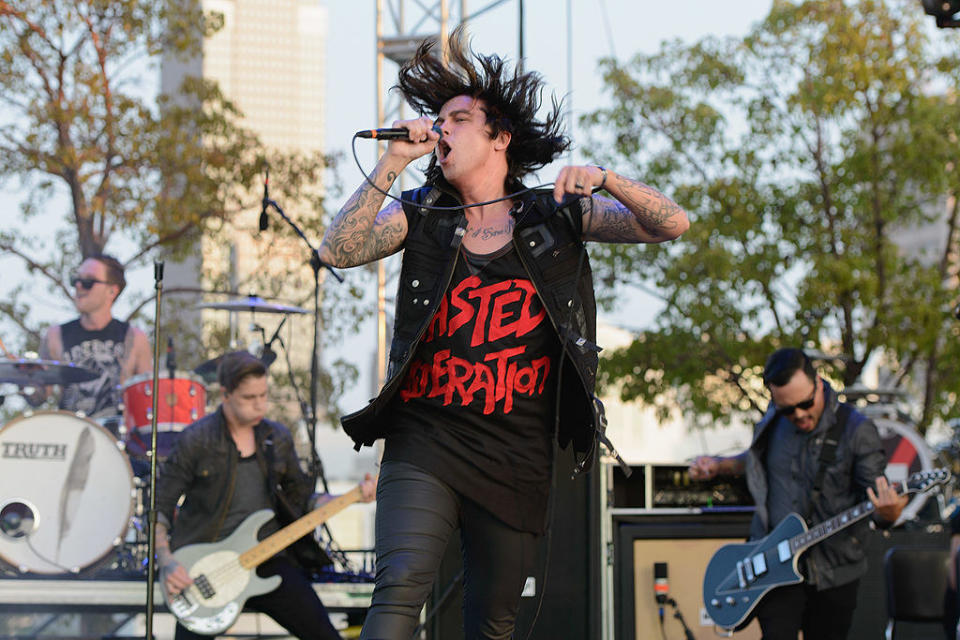 Lead singer Kellen Quinn of "Sleeping with Sirens" sings into a microphone on stage