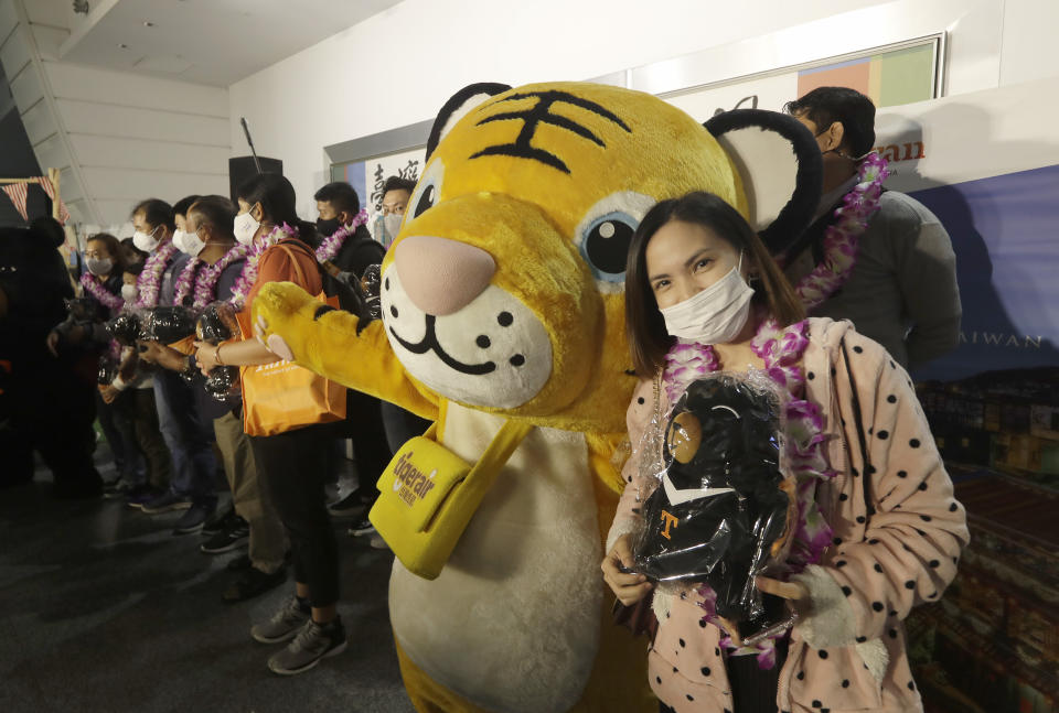 First group of foreign travelers pose for photos at Taoyuan International Airport in Taoyuan, Northern Taiwan, Thursday, Oct. 13, 2022. Taiwan announced that it will end mandatory COVID-19 quarantines for people arriving from overseas beginning Oct. 13. The Central Epidemic Command Center announced that the previous weeklong requirement will be replaced with a seven-day self-monitoring period. (AP Photo/Chiang Ying-ying)